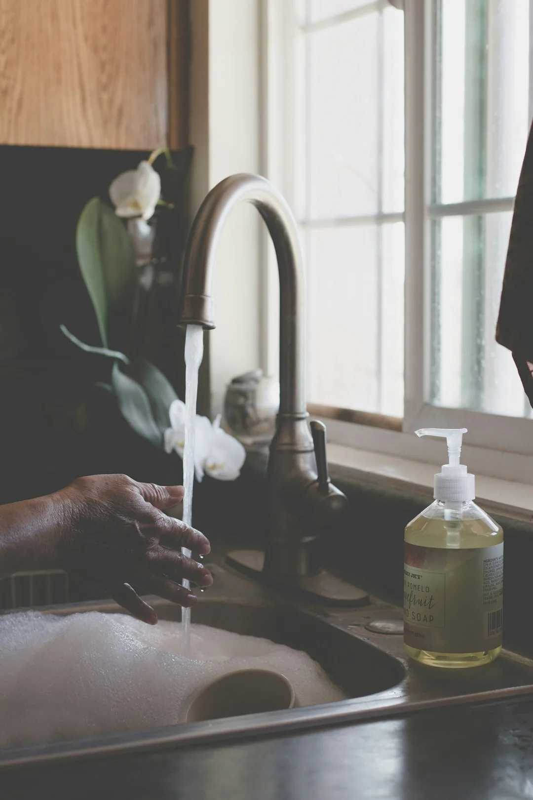 A man cleaning a glass door indoors using a spray bottle and cloth.