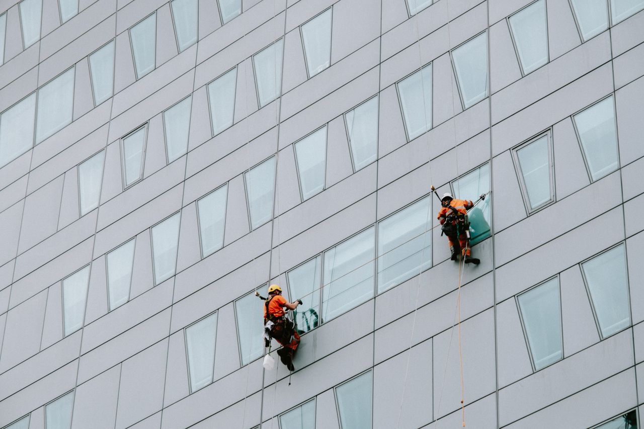 Window cleaning specialists in safety equipment washing a skyscraper exterior.